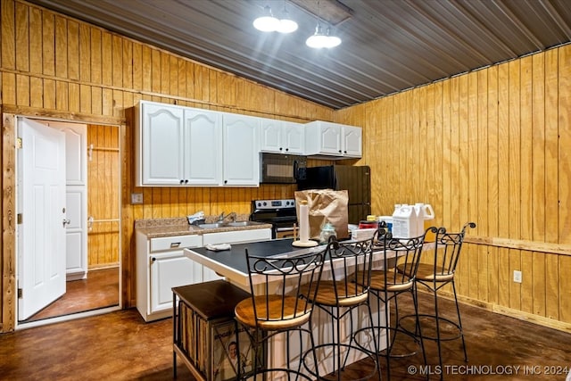 kitchen featuring a kitchen breakfast bar, wood walls, vaulted ceiling, white cabinets, and black appliances