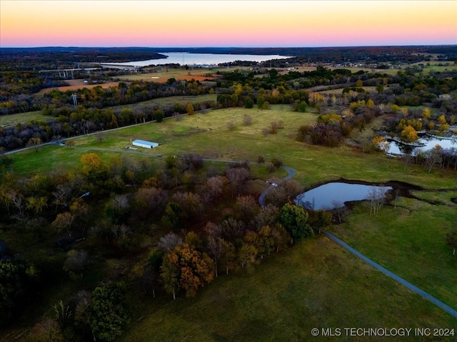 aerial view at dusk featuring a water view