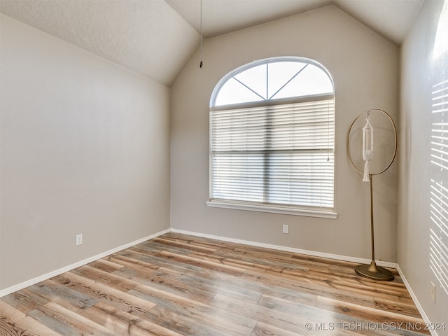 empty room featuring light wood-type flooring and vaulted ceiling