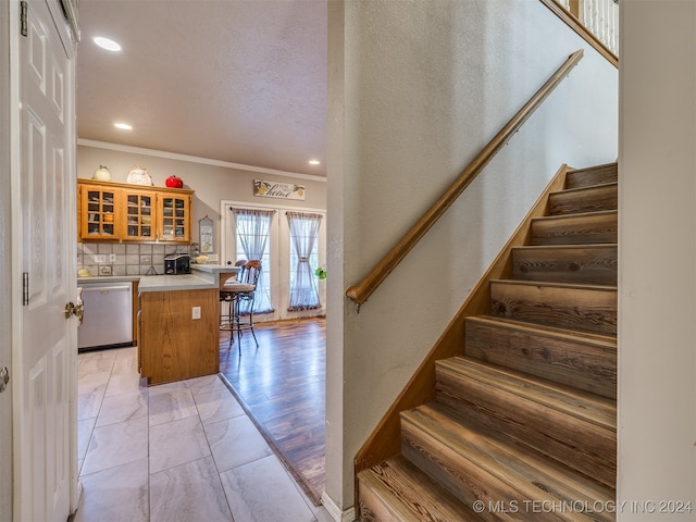 stairway featuring crown molding, french doors, a textured ceiling, and hardwood / wood-style flooring