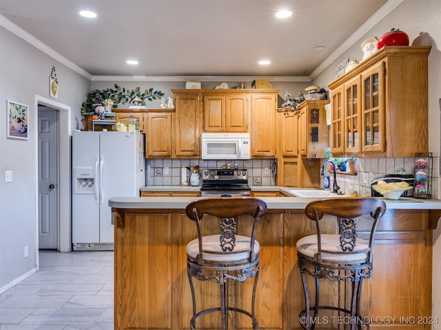 kitchen with a breakfast bar area, sink, white appliances, and ornamental molding