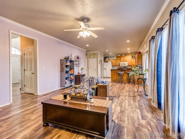 living room featuring a textured ceiling, light wood-type flooring, ceiling fan, and ornamental molding