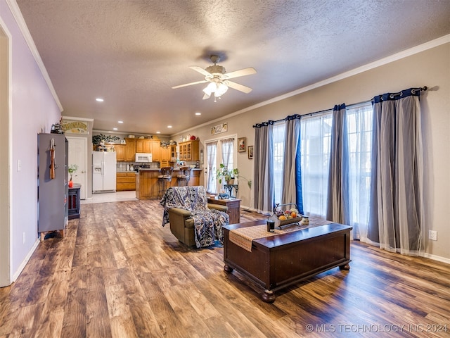 living room with wood-type flooring, plenty of natural light, and ornamental molding