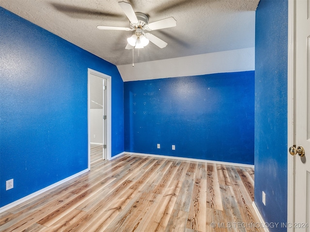 unfurnished room with a textured ceiling, ceiling fan, light hardwood / wood-style floors, and vaulted ceiling