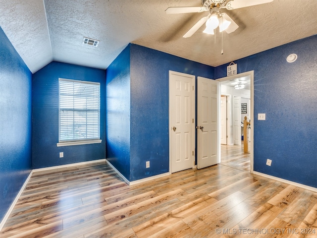 unfurnished bedroom with a textured ceiling, hardwood / wood-style flooring, ceiling fan, and lofted ceiling