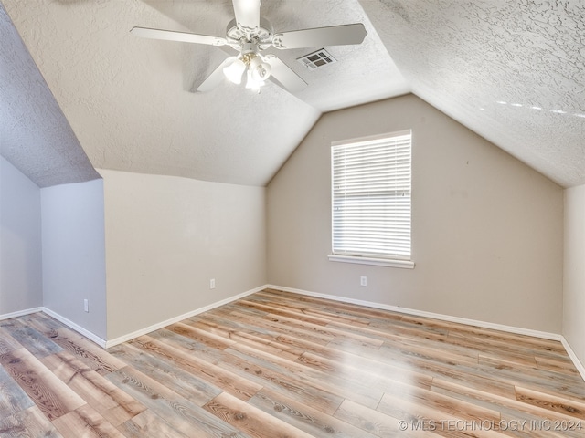 additional living space featuring ceiling fan, light hardwood / wood-style floors, a textured ceiling, and vaulted ceiling