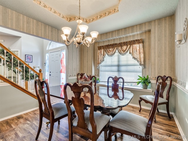 dining space with a raised ceiling, dark hardwood / wood-style floors, and a notable chandelier