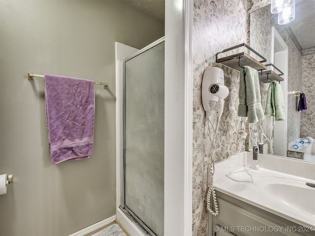 bathroom featuring a textured ceiling, vanity, and an enclosed shower