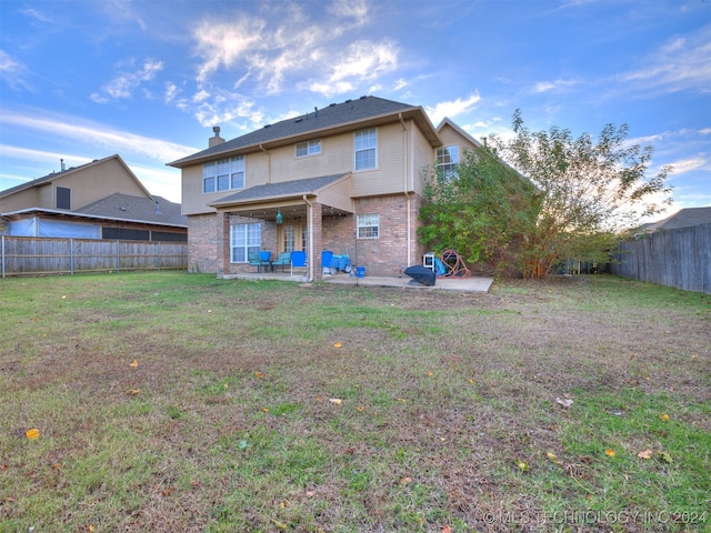 rear view of house featuring ceiling fan, a patio area, and a lawn