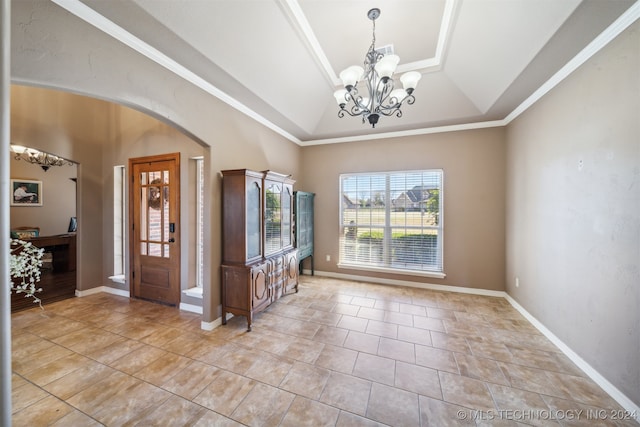 tiled foyer entrance with a raised ceiling, an inviting chandelier, and crown molding