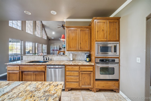 kitchen with sink, decorative backsplash, ornamental molding, appliances with stainless steel finishes, and kitchen peninsula