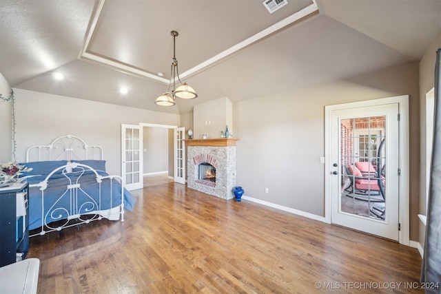 living room featuring lofted ceiling, a fireplace, french doors, and hardwood / wood-style flooring