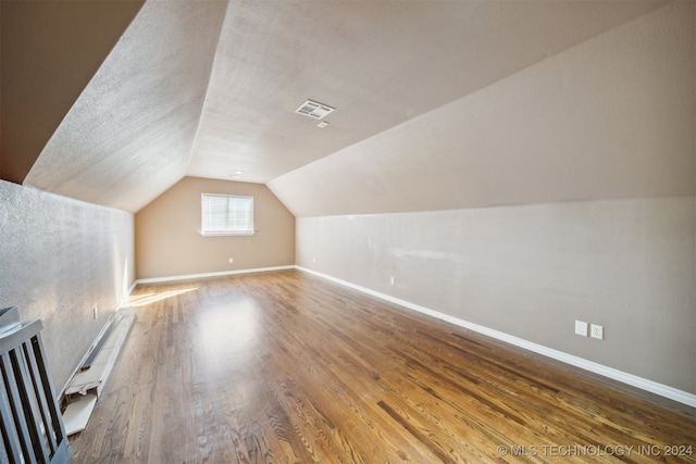 additional living space featuring wood-type flooring and vaulted ceiling