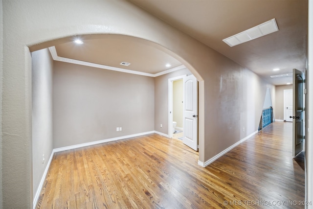 empty room featuring wood-type flooring and ornamental molding