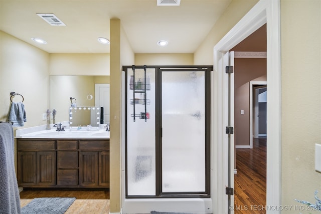 bathroom featuring a shower with shower door, wood-type flooring, and vanity