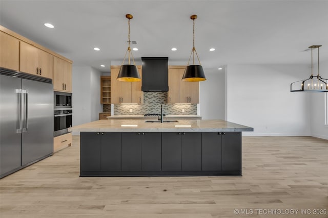 kitchen with premium range hood, built in appliances, light brown cabinetry, and decorative light fixtures