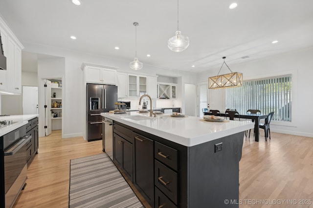 kitchen featuring pendant lighting, white cabinets, sink, an island with sink, and stainless steel appliances