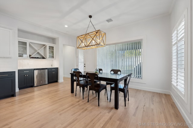 dining space with a chandelier, ornamental molding, and light hardwood / wood-style flooring