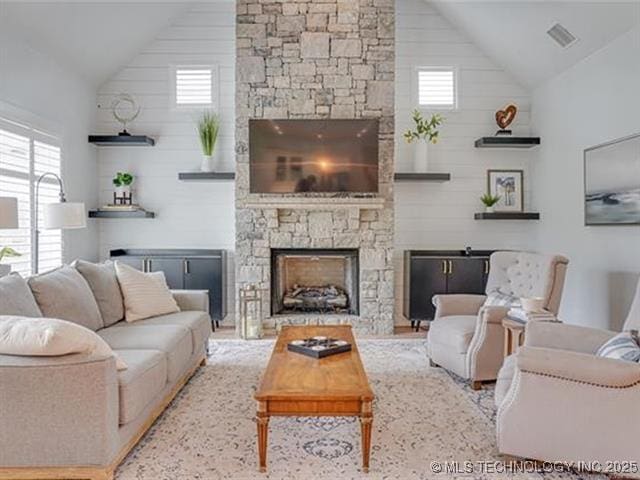 living room with a stone fireplace, a wealth of natural light, wood walls, and vaulted ceiling