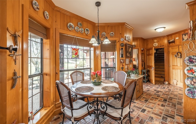 dining space featuring a notable chandelier and wood walls