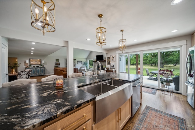 kitchen featuring stainless steel appliances, hanging light fixtures, dark stone counters, vaulted ceiling, and light wood-type flooring