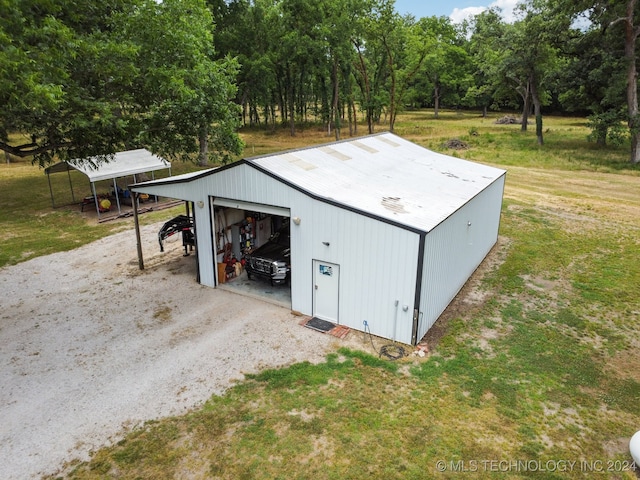 view of outdoor structure with a yard, a carport, and a garage