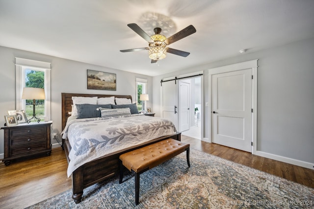 bedroom with hardwood / wood-style floors, a barn door, and ceiling fan