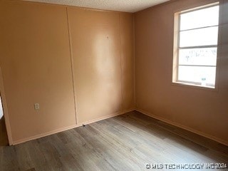 spare room featuring wood-type flooring, a textured ceiling, and plenty of natural light