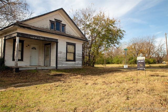 view of side of property with covered porch and a yard