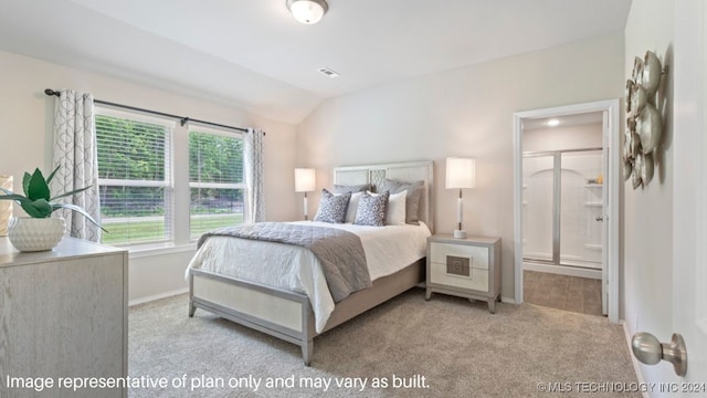 bedroom with ensuite bathroom, vaulted ceiling, and light colored carpet