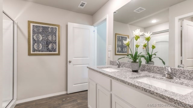 bathroom featuring hardwood / wood-style flooring, vanity, and walk in shower