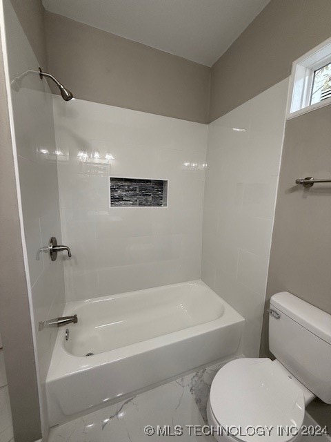 bathroom featuring tiled shower / bath combo and toilet