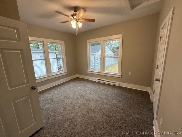 carpeted spare room featuring ceiling fan, a wealth of natural light, and a baseboard heating unit