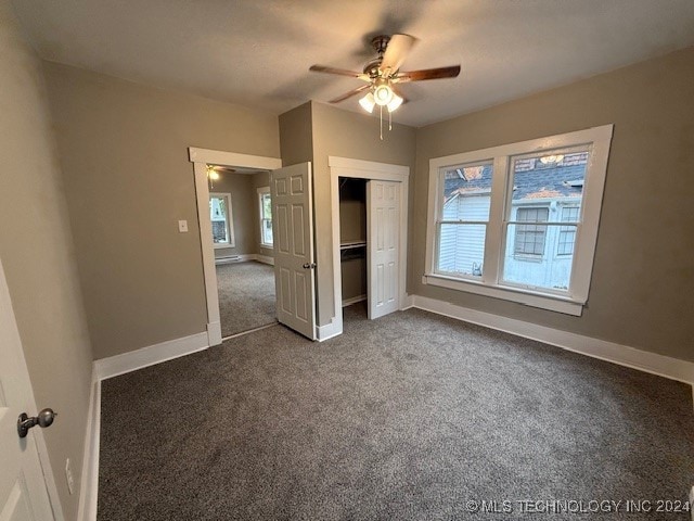 unfurnished bedroom with multiple windows, ceiling fan, a closet, and dark carpet