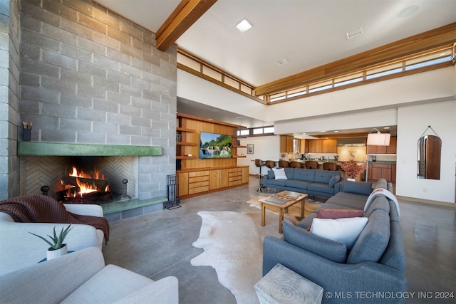 living room with concrete flooring, a towering ceiling, and a large fireplace