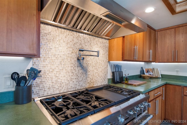 kitchen with lofted ceiling, decorative backsplash, high end range, and wall chimney range hood