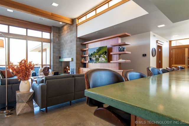 interior space with beamed ceiling, a large fireplace, and concrete flooring