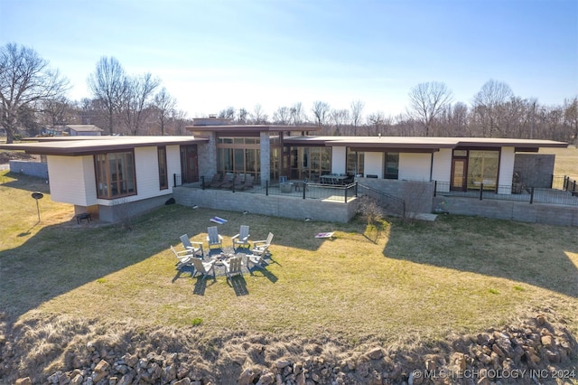 rear view of house with a fire pit, a patio area, and a yard