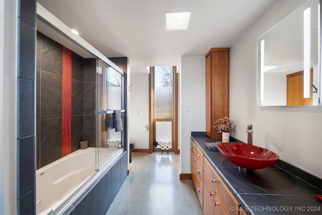 full bathroom with vanity, toilet, concrete floors, and bath / shower combo with glass door