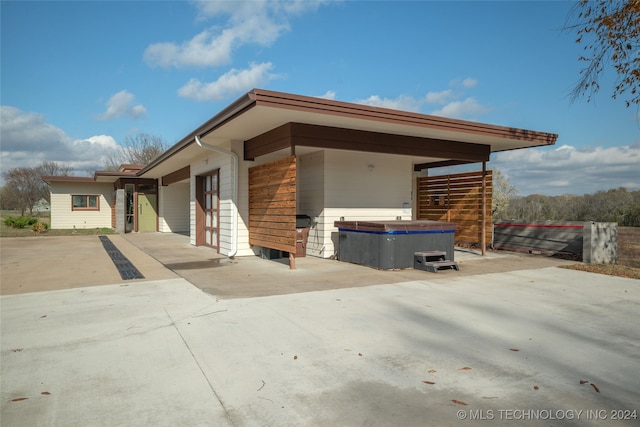 view of side of property featuring a garage, a patio, and a hot tub