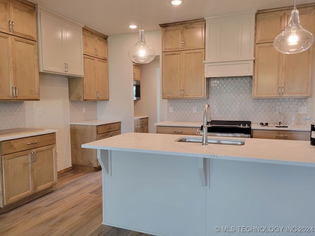 kitchen with light hardwood / wood-style floors, sink, hanging light fixtures, and tasteful backsplash