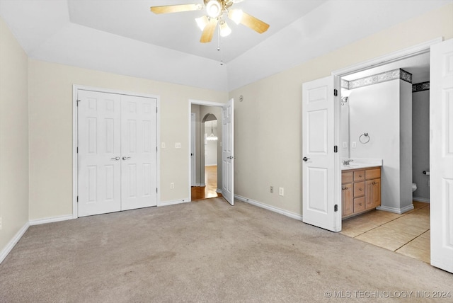 unfurnished bedroom with connected bathroom, ceiling fan, sink, light colored carpet, and a closet