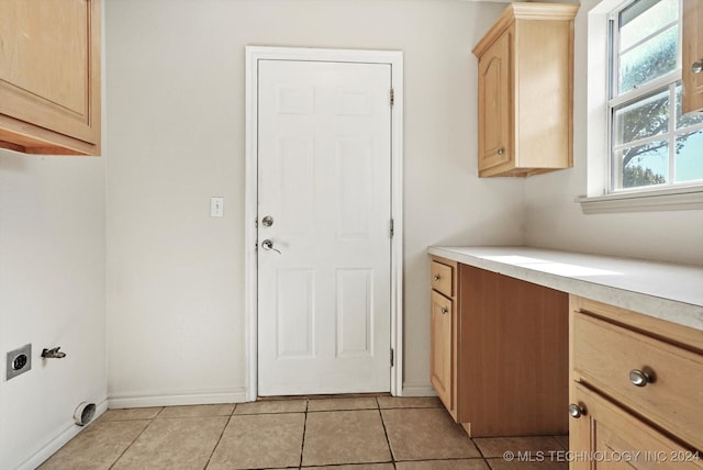 laundry area with hookup for an electric dryer, cabinets, and light tile patterned floors