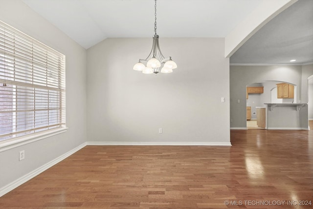 spare room with a notable chandelier, crown molding, dark wood-type flooring, and vaulted ceiling