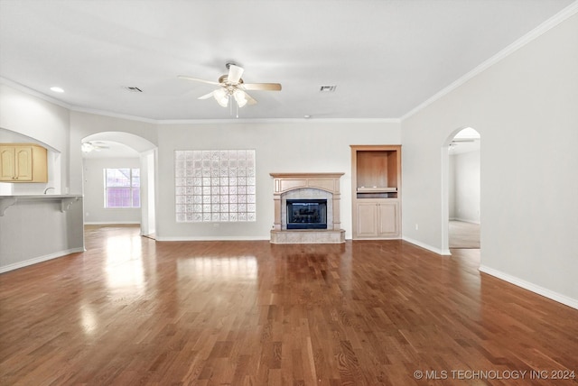 unfurnished living room featuring wood-type flooring, ornamental molding, and a tiled fireplace