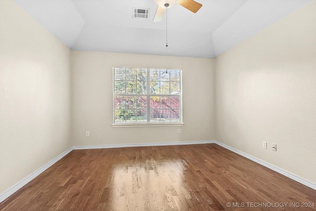 empty room with ceiling fan, dark hardwood / wood-style flooring, and vaulted ceiling