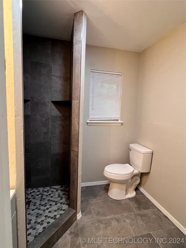 bathroom featuring tile patterned floors, toilet, and tiled shower