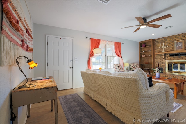 bedroom featuring a fireplace, hardwood / wood-style floors, and ceiling fan