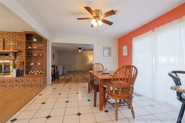 dining room with a fireplace, light hardwood / wood-style floors, built in features, and ceiling fan