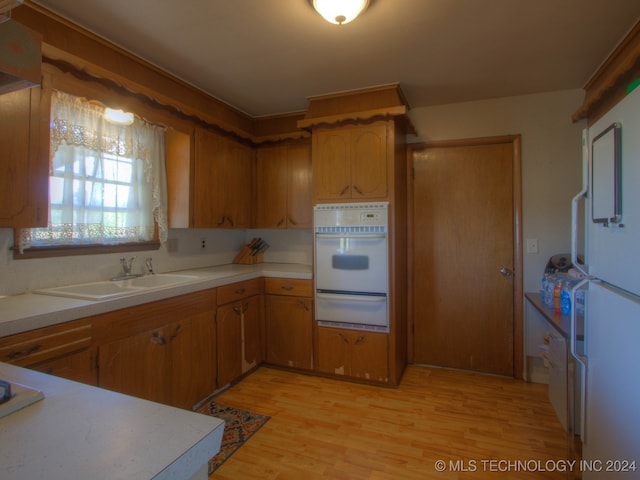 kitchen with white appliances, sink, and light hardwood / wood-style flooring